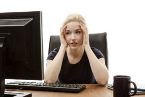 43400815 - woman sitting at her desk with her head in her hands stressed out